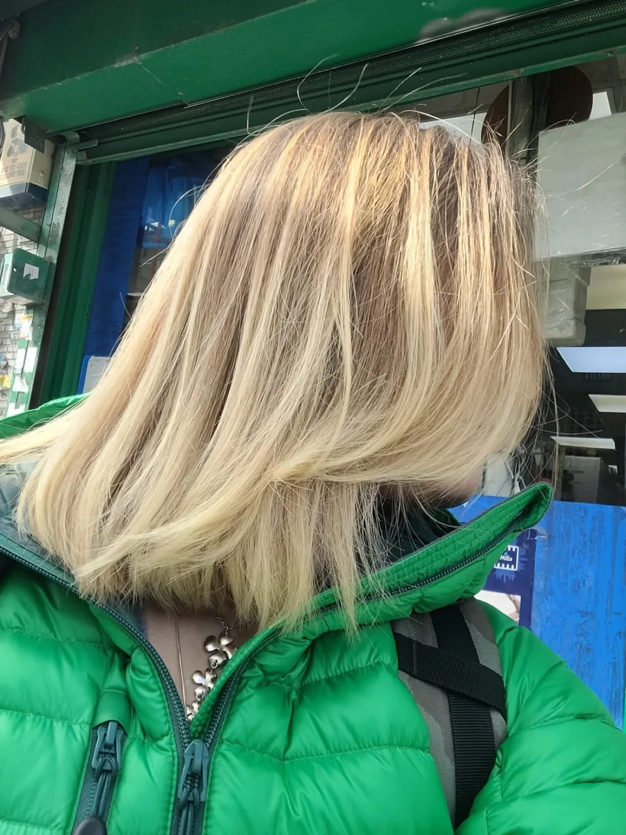 A client outside the salon with a freshly cut blonde shoulder-length lob