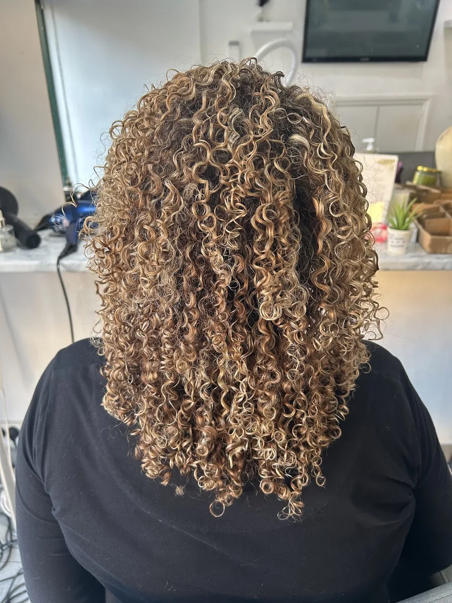 A bouncy shoulder-length curly bob in warm honey blonde