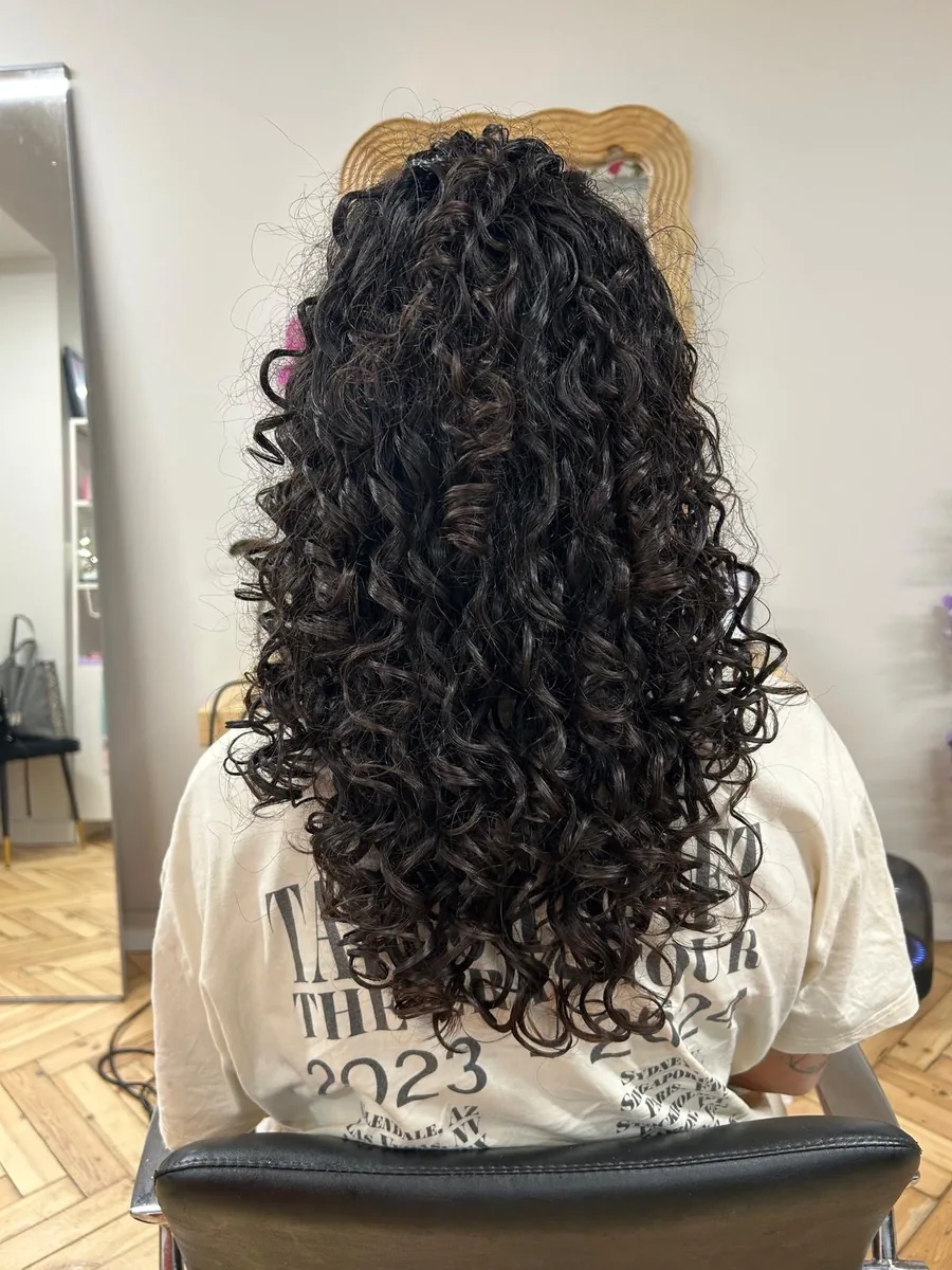 Long dark defined curls falling past the shoulders after a curl cut