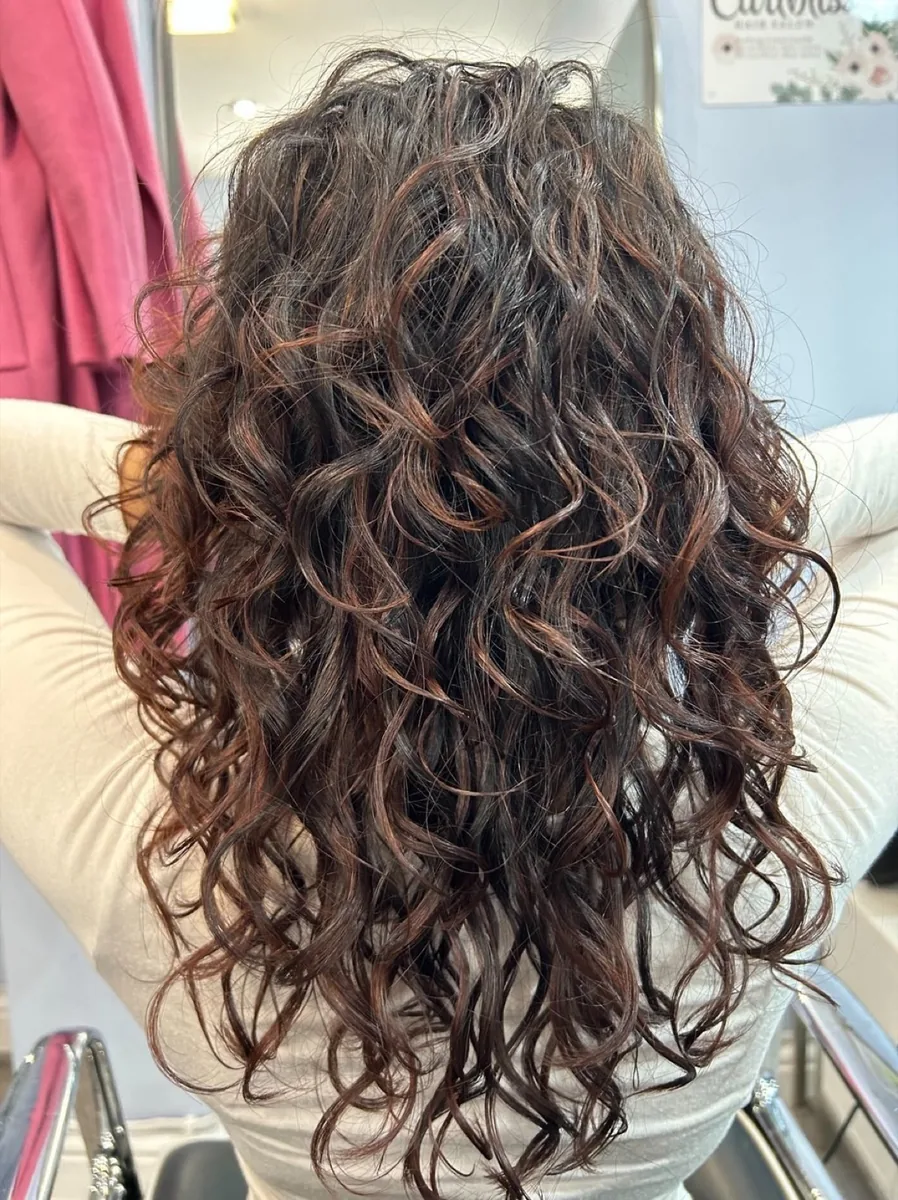 Long dark brown curls lit with warm caramel highlights