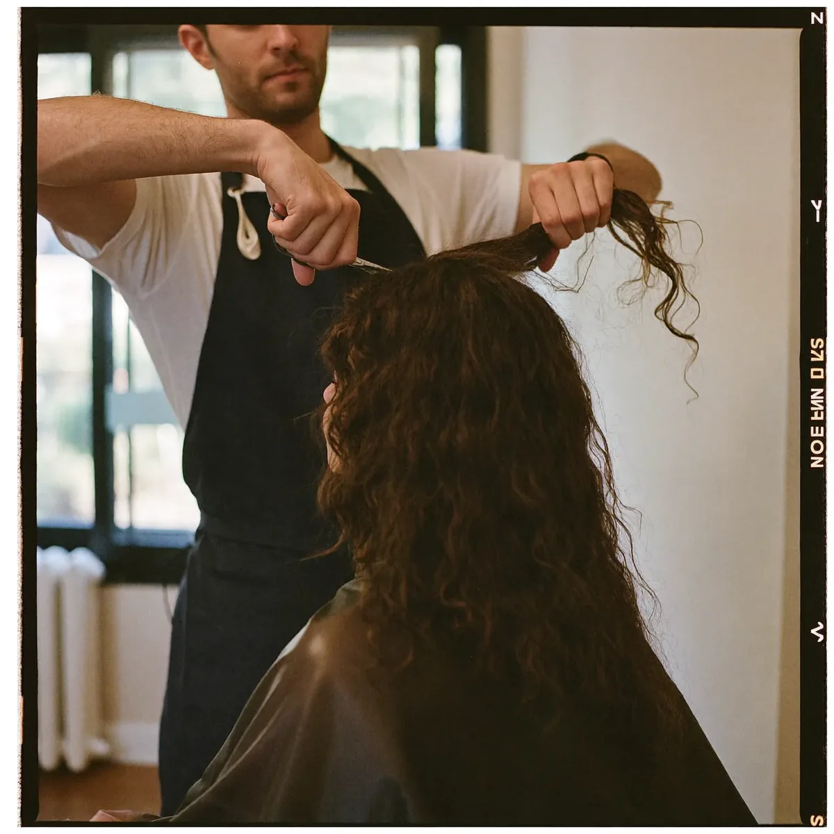 A stylist cutting long curly hair in the salon