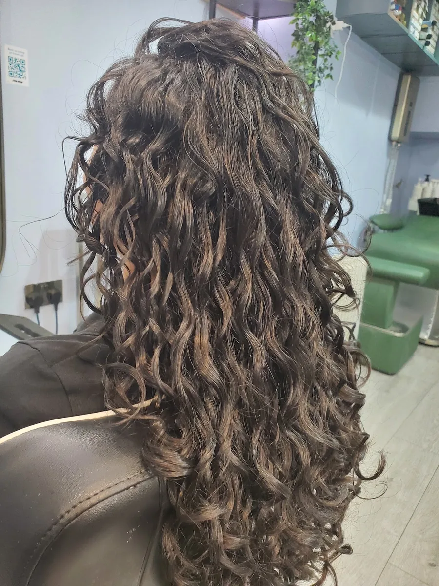 Close detail of long layered brown curls with caramel tones after styling